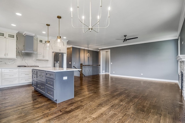 kitchen with white cabinetry, a kitchen island, decorative light fixtures, stainless steel appliances, and ornamental molding