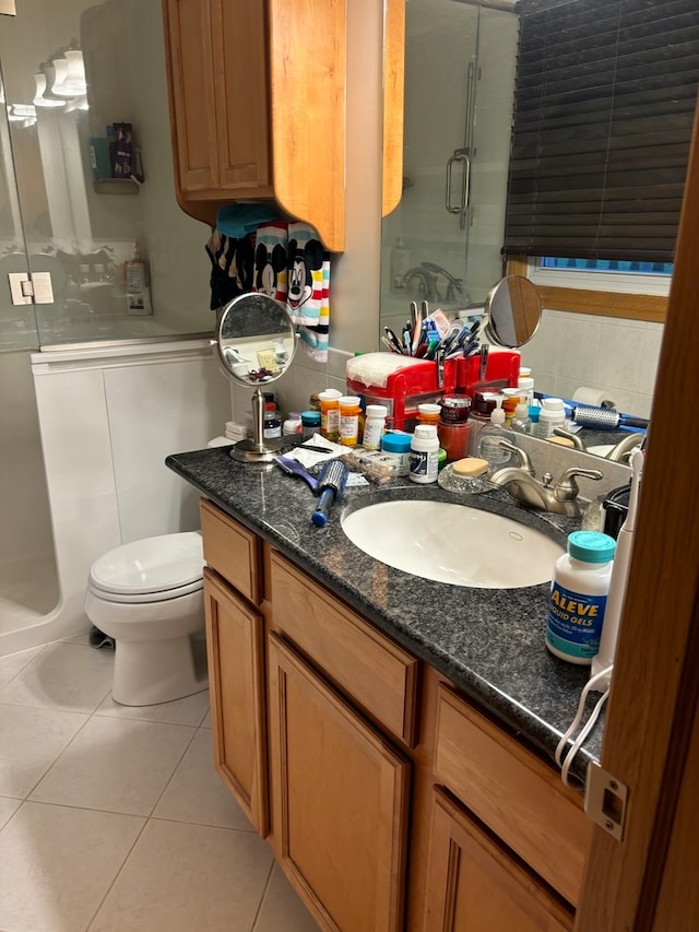 bathroom featuring vanity, a shower with door, tile patterned flooring, and toilet