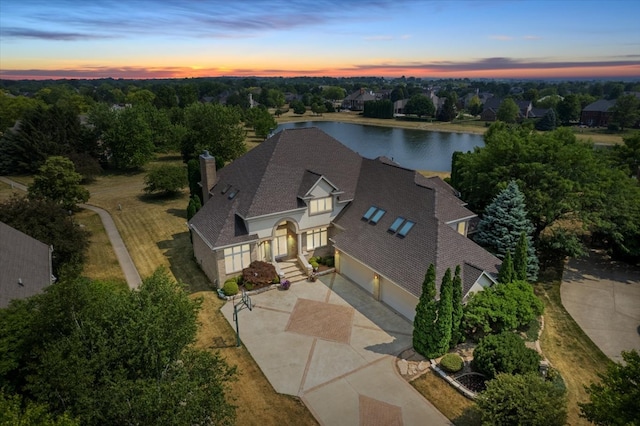 aerial view at dusk featuring a water view