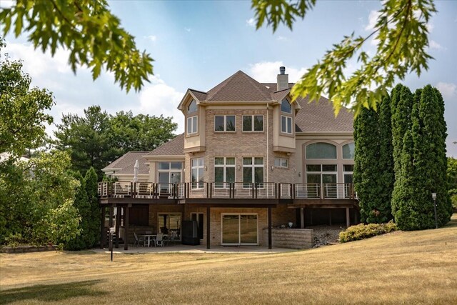 back of property featuring a deck, a patio area, and a lawn