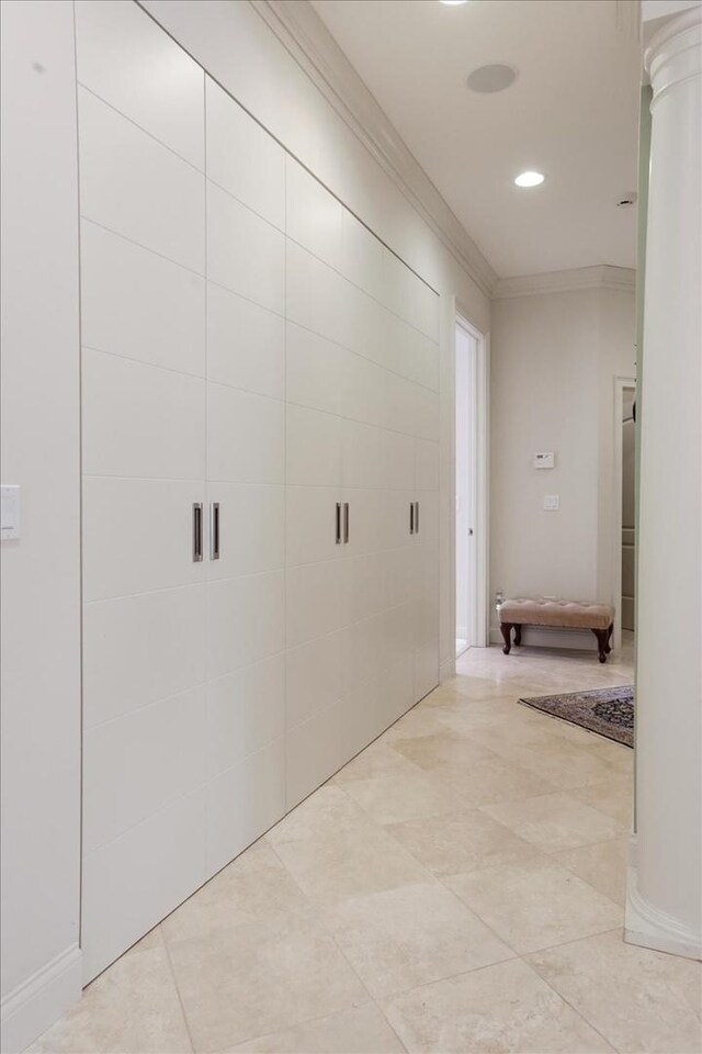 hall featuring crown molding, ornate columns, and light tile patterned floors