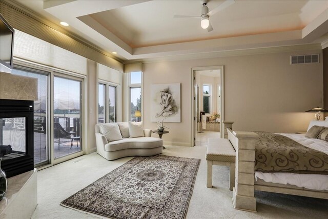 carpeted bedroom with a fireplace, a raised ceiling, access to outside, and ceiling fan