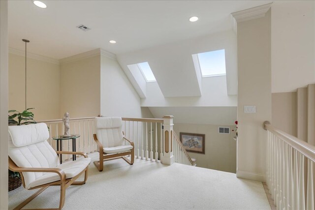 sitting room with ornamental molding, carpet flooring, and vaulted ceiling with skylight