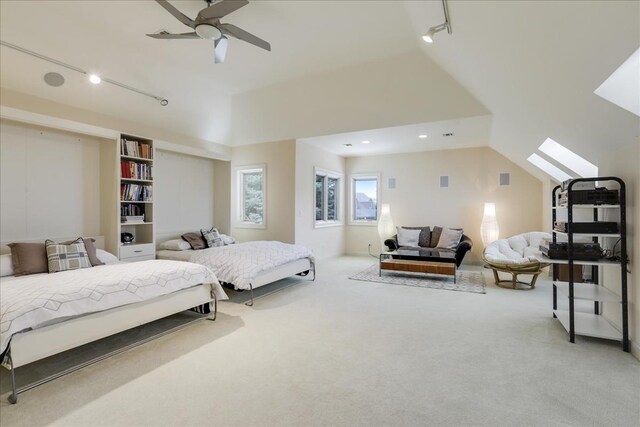 carpeted bedroom with a skylight, rail lighting, and ceiling fan