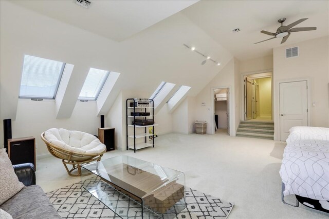 carpeted bedroom with vaulted ceiling with skylight and ceiling fan