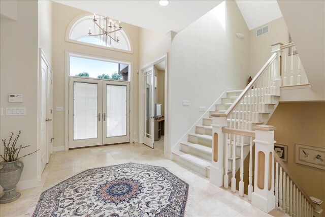 tiled foyer with an inviting chandelier, french doors, and a high ceiling