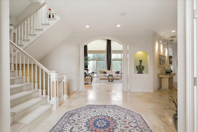 foyer entrance with tile patterned floors and crown molding