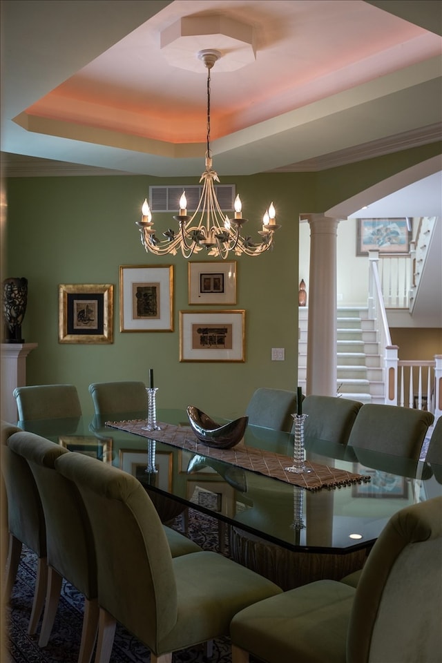 dining room featuring decorative columns, a chandelier, and a tray ceiling