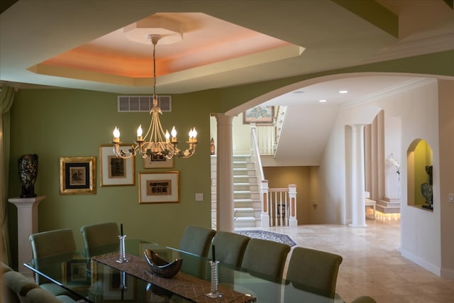 dining space featuring an inviting chandelier, decorative columns, crown molding, tile patterned floors, and a raised ceiling