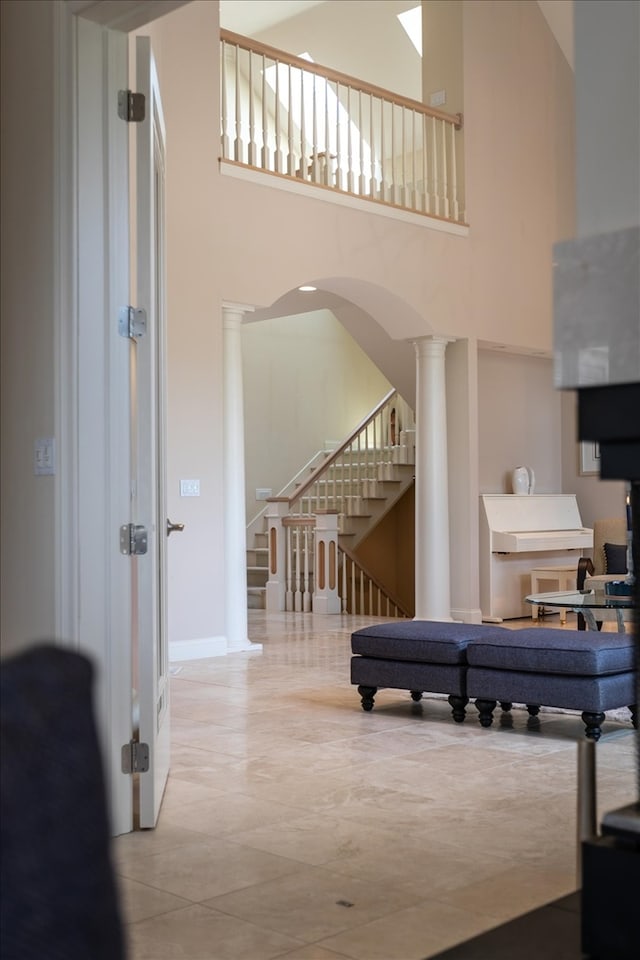 interior space with tile patterned flooring, decorative columns, and a high ceiling