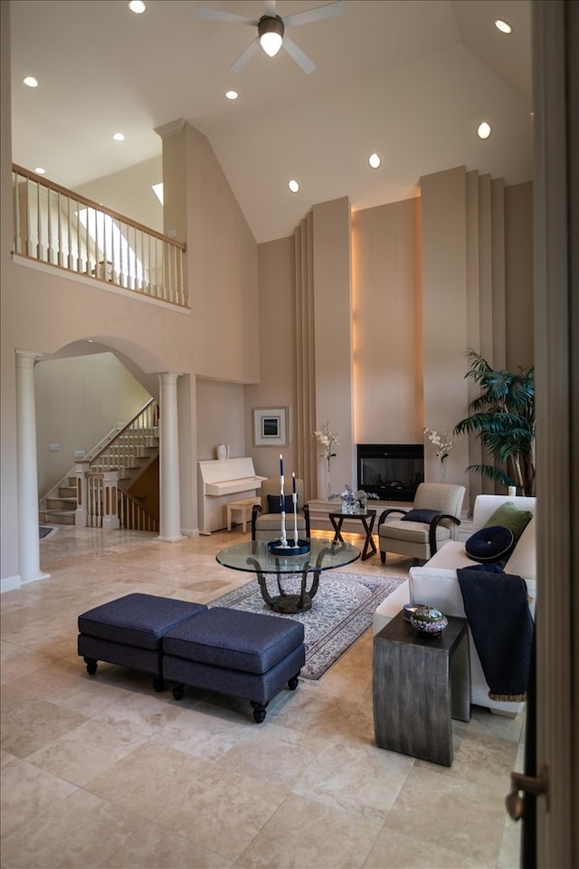 tiled living room featuring high vaulted ceiling, decorative columns, and ceiling fan