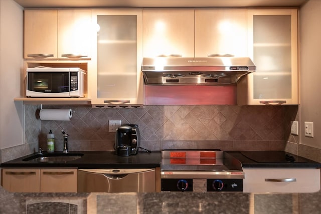 kitchen with wall chimney range hood, sink, tasteful backsplash, and cream cabinets