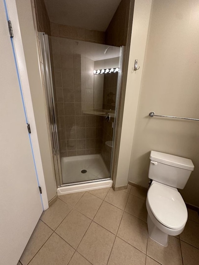 bathroom with tile patterned floors, toilet, and a shower with shower door