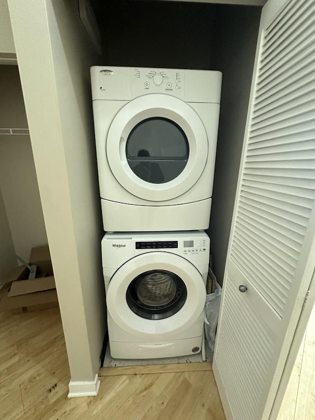 washroom with stacked washer and clothes dryer and light wood-type flooring