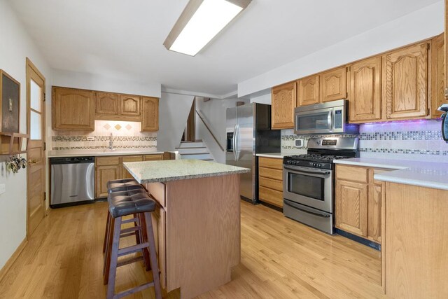 kitchen with appliances with stainless steel finishes, decorative backsplash, and light wood-type flooring