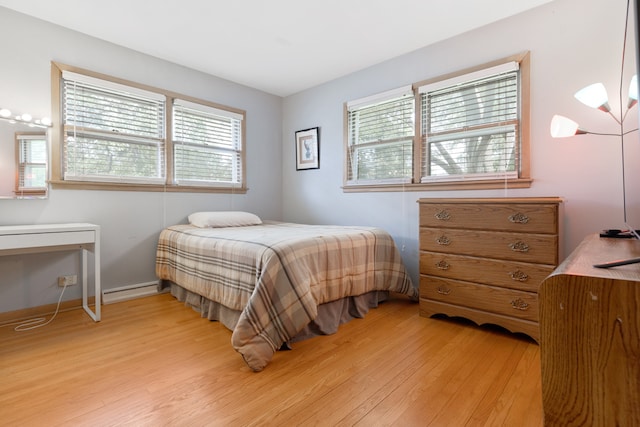 bedroom with baseboard heating, multiple windows, and light wood-type flooring