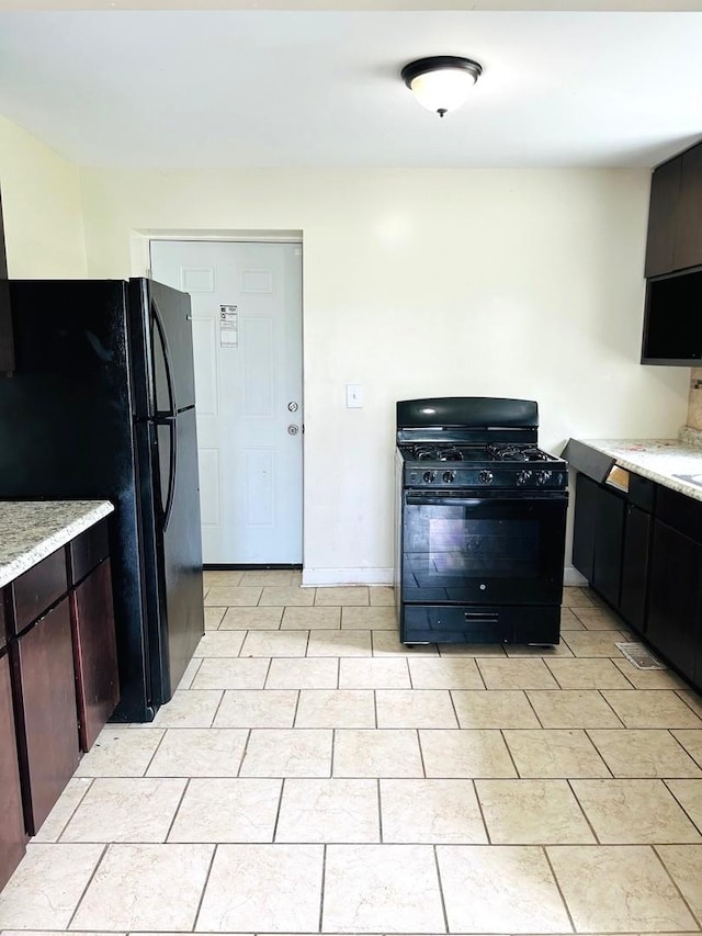 kitchen featuring dark brown cabinetry, black appliances, and light tile patterned flooring