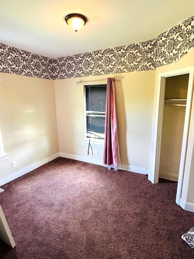 unfurnished bedroom featuring dark carpet and a closet