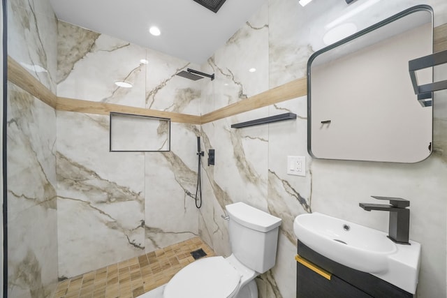 bathroom with tile walls, tiled shower, vanity, and toilet