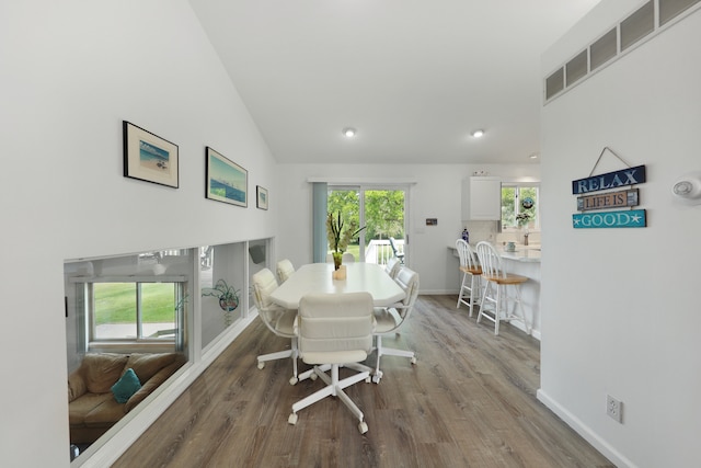 dining space with hardwood / wood-style flooring, vaulted ceiling, and a healthy amount of sunlight