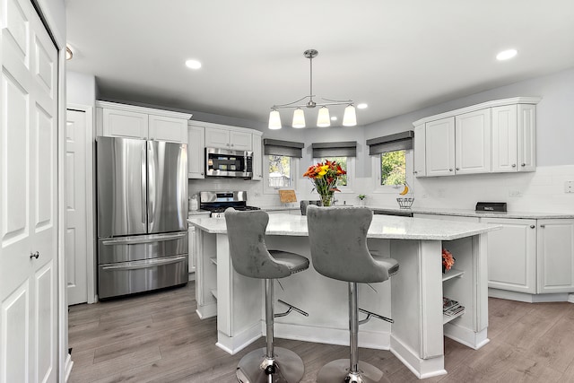 kitchen with a kitchen island, white cabinetry, decorative light fixtures, and stainless steel appliances