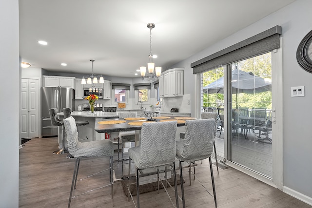 dining space with sink, a chandelier, and light hardwood / wood-style flooring