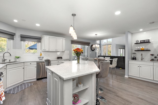 kitchen featuring backsplash, sink, a center island, white cabinets, and light hardwood / wood-style floors