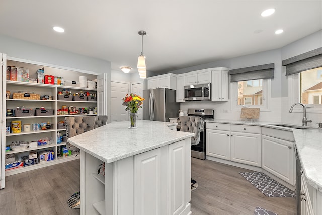 kitchen featuring appliances with stainless steel finishes, white cabinetry, sink, and pendant lighting