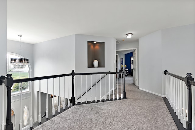 hallway with carpet floors and an inviting chandelier