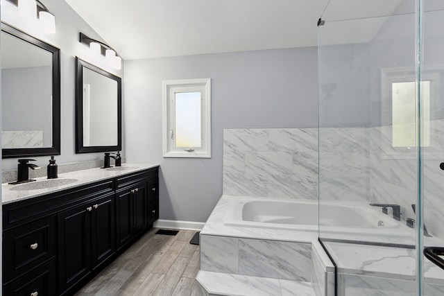 bathroom featuring vanity, hardwood / wood-style flooring, lofted ceiling, and plus walk in shower