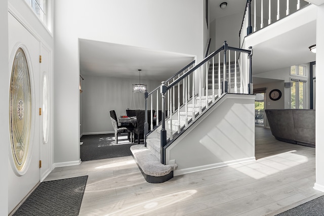 foyer entrance with light hardwood / wood-style floors, a high ceiling, and a chandelier