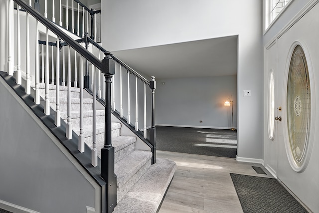 foyer with light hardwood / wood-style floors and a towering ceiling