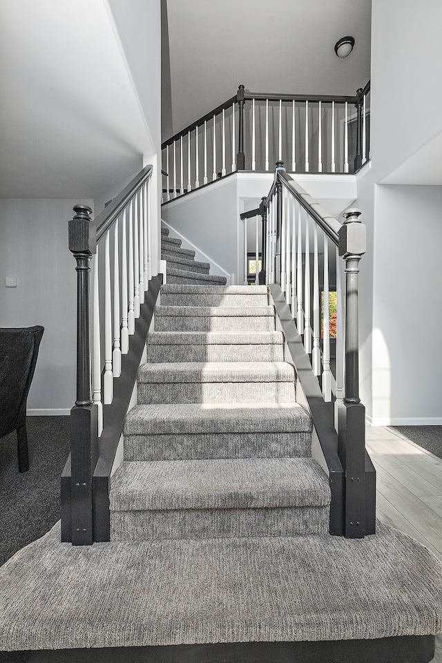 staircase featuring carpet floors and a high ceiling