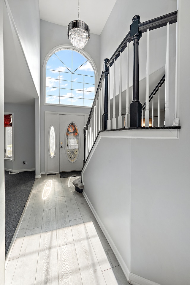 entryway with a chandelier, light wood-type flooring, and a high ceiling