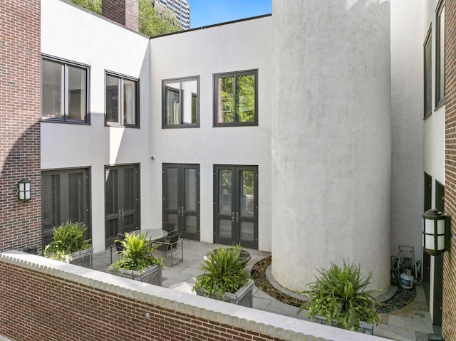 rear view of property with stucco siding, french doors, and a patio