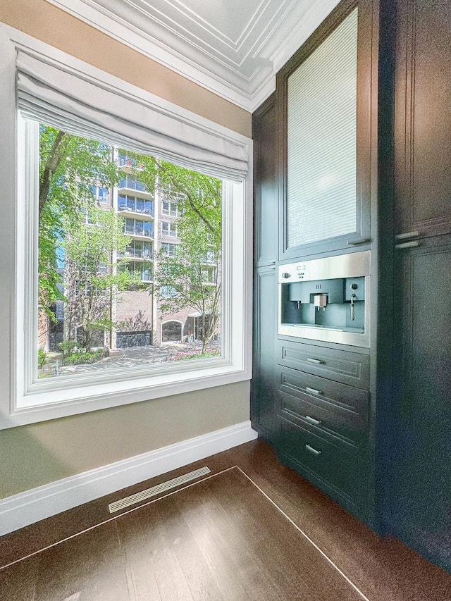 interior space featuring wood finished floors, baseboards, visible vents, and ornamental molding