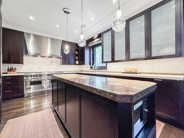 kitchen with double oven range, a kitchen island, dark wood-style flooring, decorative backsplash, and wall chimney exhaust hood