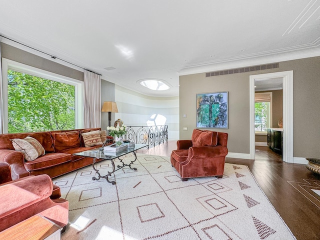 living area featuring visible vents, ornamental molding, baseboards, and wood finished floors