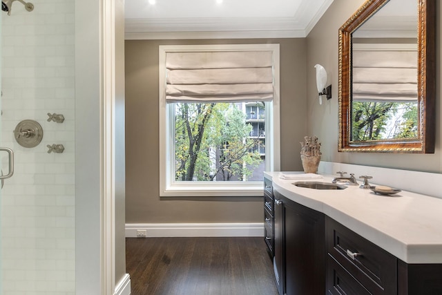 bathroom featuring baseboards, wood finished floors, ornamental molding, and tiled shower