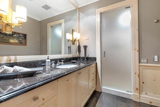 bathroom with visible vents, vanity, crown molding, and wood finished floors