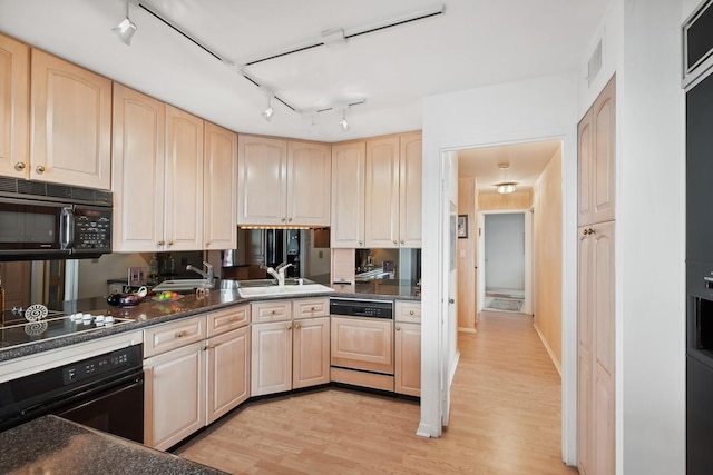 kitchen featuring black appliances, light wood-style flooring, light brown cabinets, and a sink