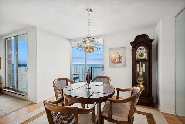 dining area with a notable chandelier, a water view, light wood-style floors, a wall of windows, and baseboards