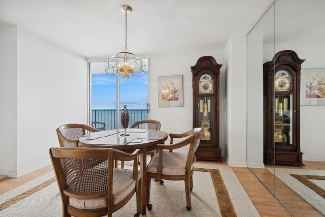 dining room featuring a chandelier, baseboards, and light wood finished floors