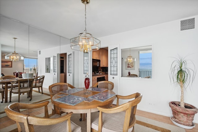 dining room with light wood-type flooring, visible vents, baseboards, and an inviting chandelier