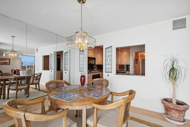 dining room featuring a chandelier, visible vents, and light wood-style flooring