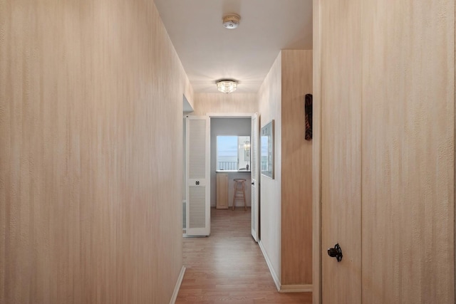 hallway featuring light wood-type flooring and baseboards