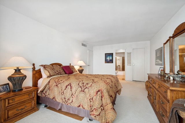 bedroom featuring light carpet, visible vents, and ensuite bathroom