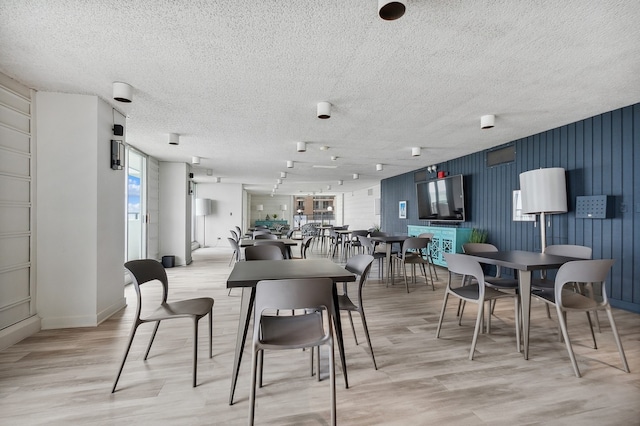 dining area featuring light wood-type flooring, plenty of natural light, and a textured ceiling