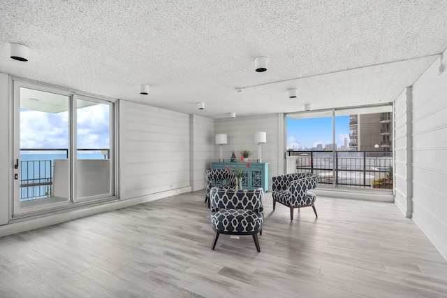 sitting room featuring floor to ceiling windows, plenty of natural light, and light wood finished floors