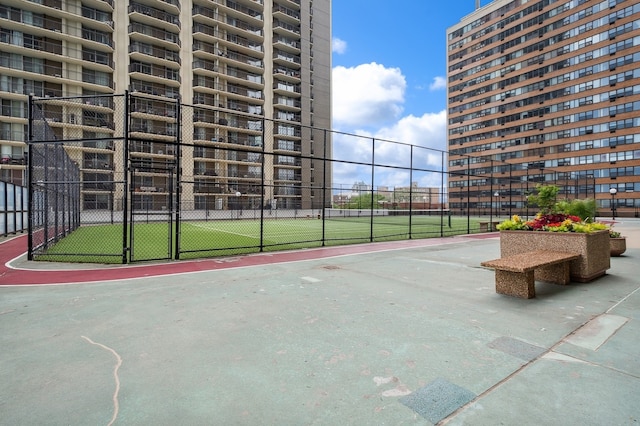 view of property's community featuring a tennis court and fence